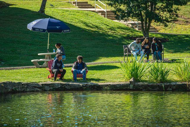 students sitting by pond